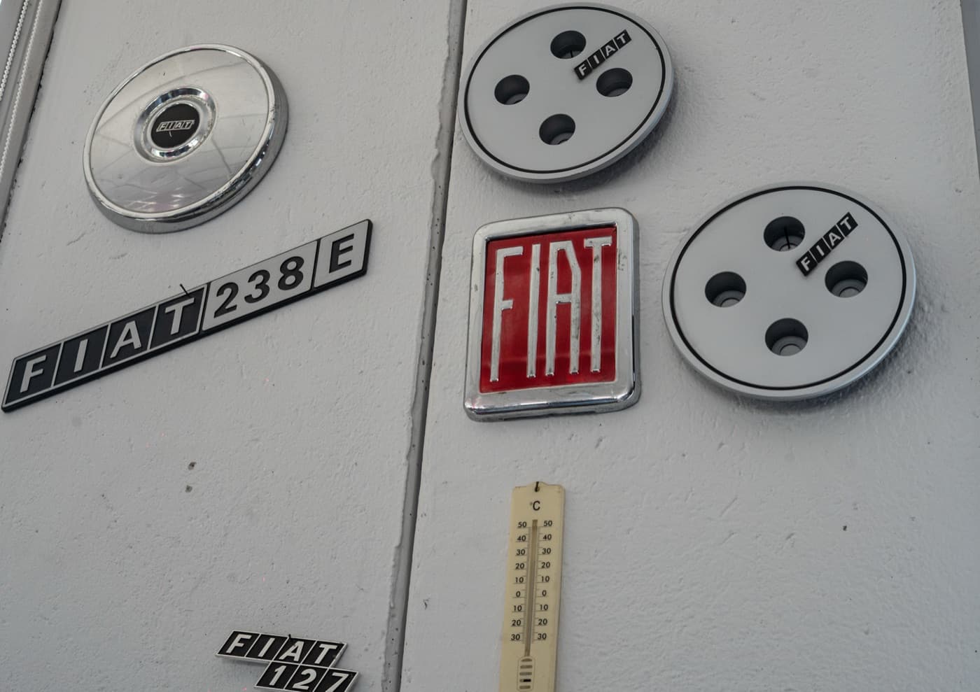Coppe ruota e fregi FIAT d'epoca appesi alla parete del negozio